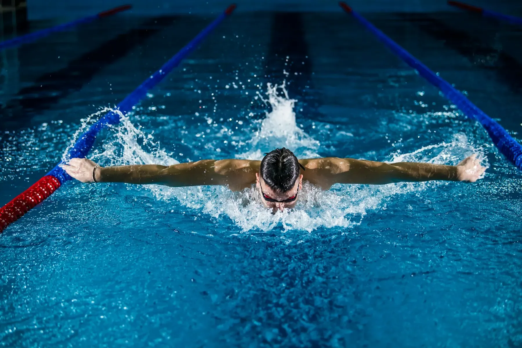 Nadador ejecutando braza en piscina, entrenamiento deportivo de alta exigencia