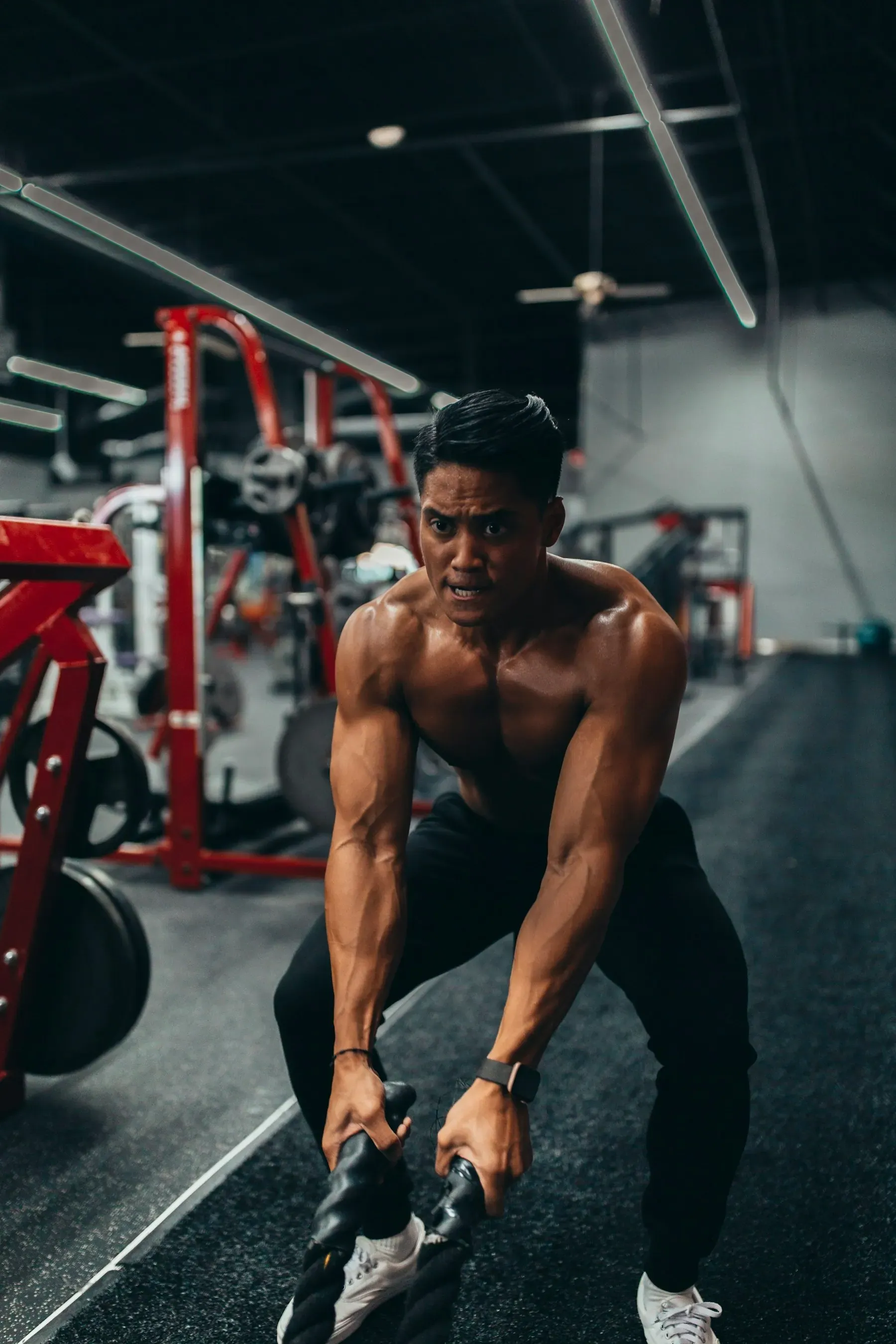 Deportista realizando ejercicio intenso con cuerdas de batalla, readaptación funcional